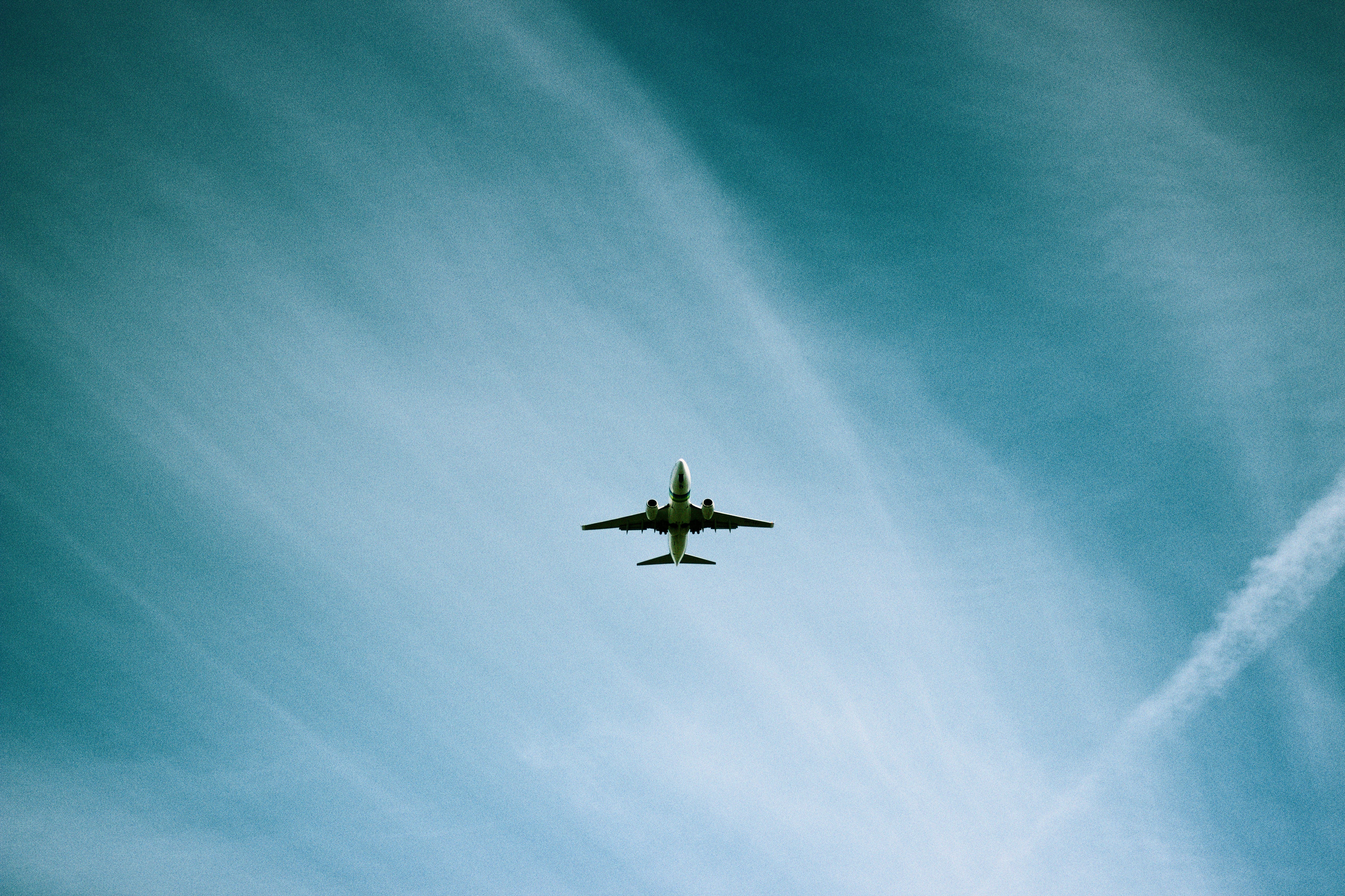 white airplane flying under blue sky